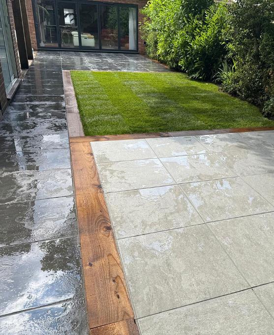 View of new garden including patio and sleeper framed grass area